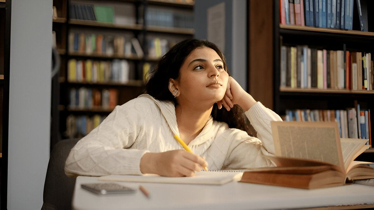 A woman thoughtfully examines books at a table, contemplating her choice of the right coaching institute.