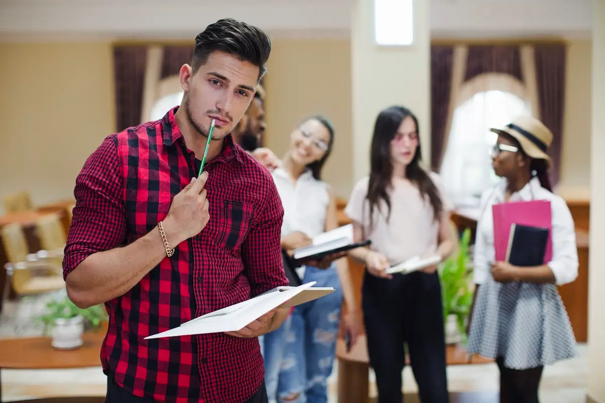 A man stands before a group of students, holding a clipboard, likely discussing the NDA 2 application form for 2023.