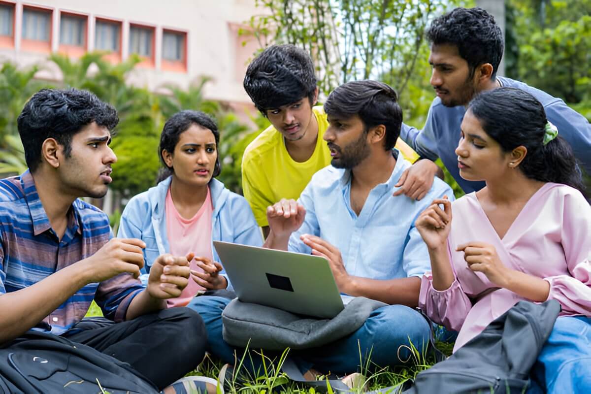 A group of young individuals seated on the grass, engaged with a laptop, exploring the Secrets Behind Veron Success.