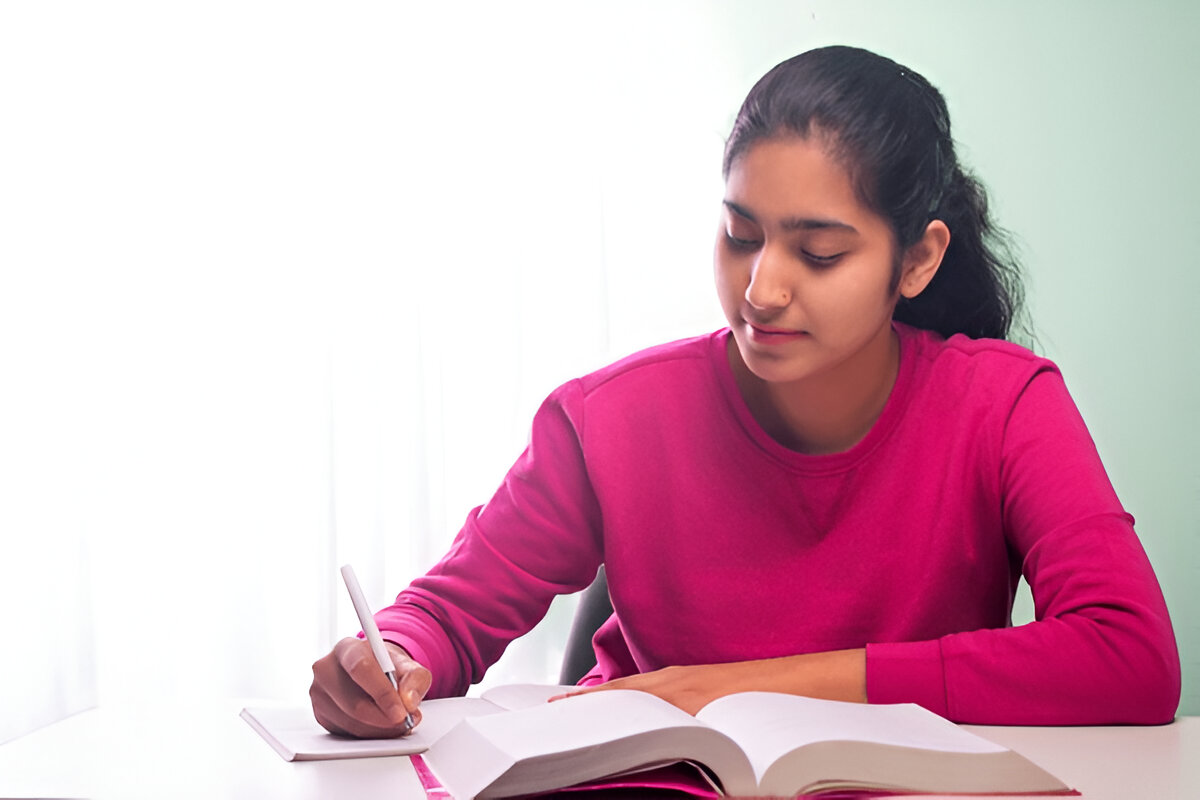 A young girl at a desk with a book and pen, focused on her studies at the Coaching Institute for Exam Excellence in Amritsar.